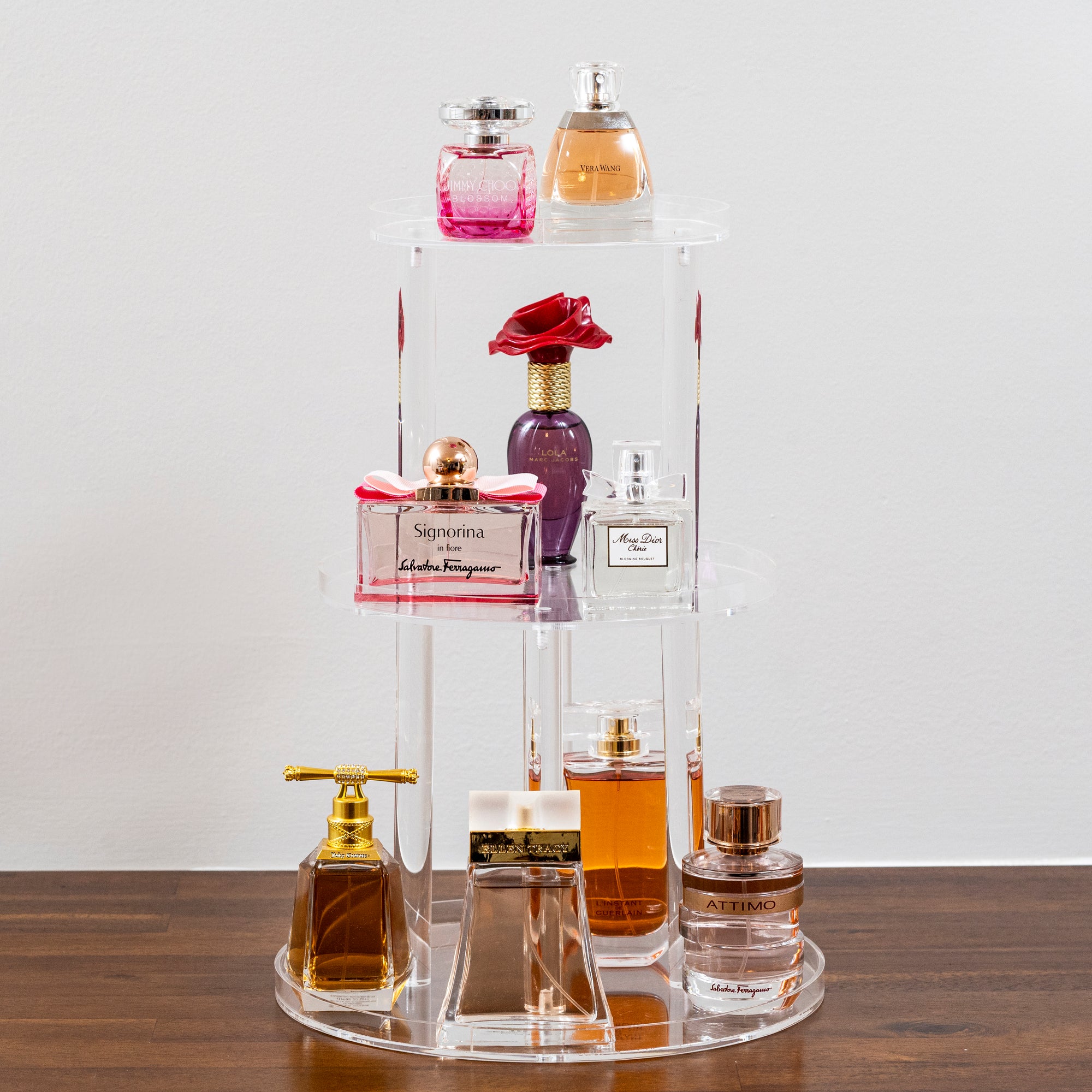 clear acrylic 3 tiered perfume stand with variety of perfumes on display