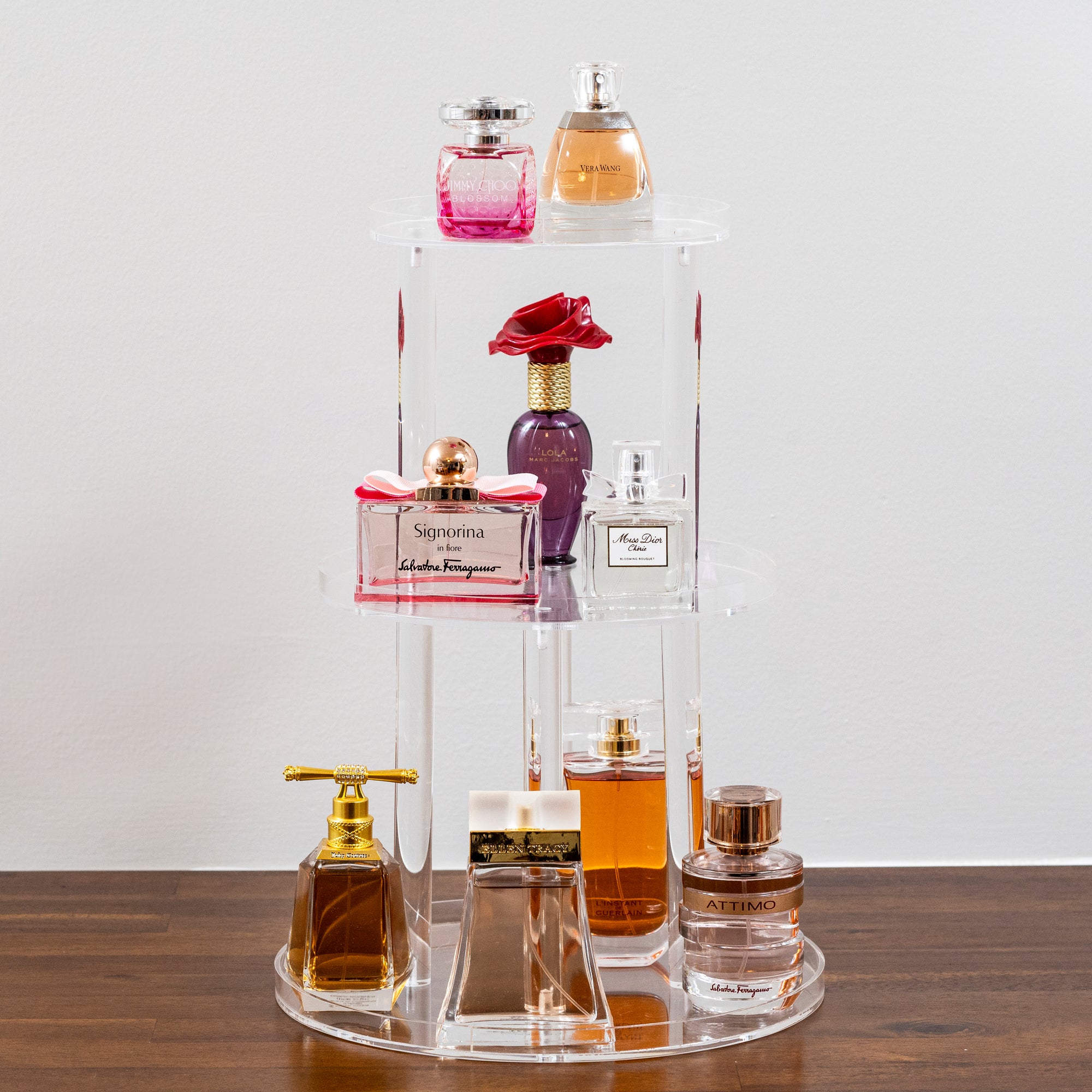 clear acrylic 3 tiered perfume stand with variety of perfumes on display 